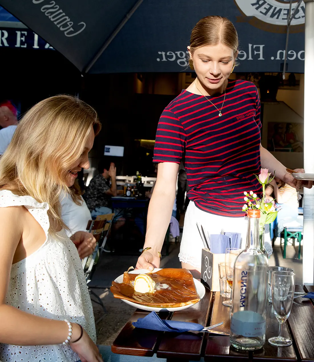 Mitarbeiter serviert einem Gast eine Speise