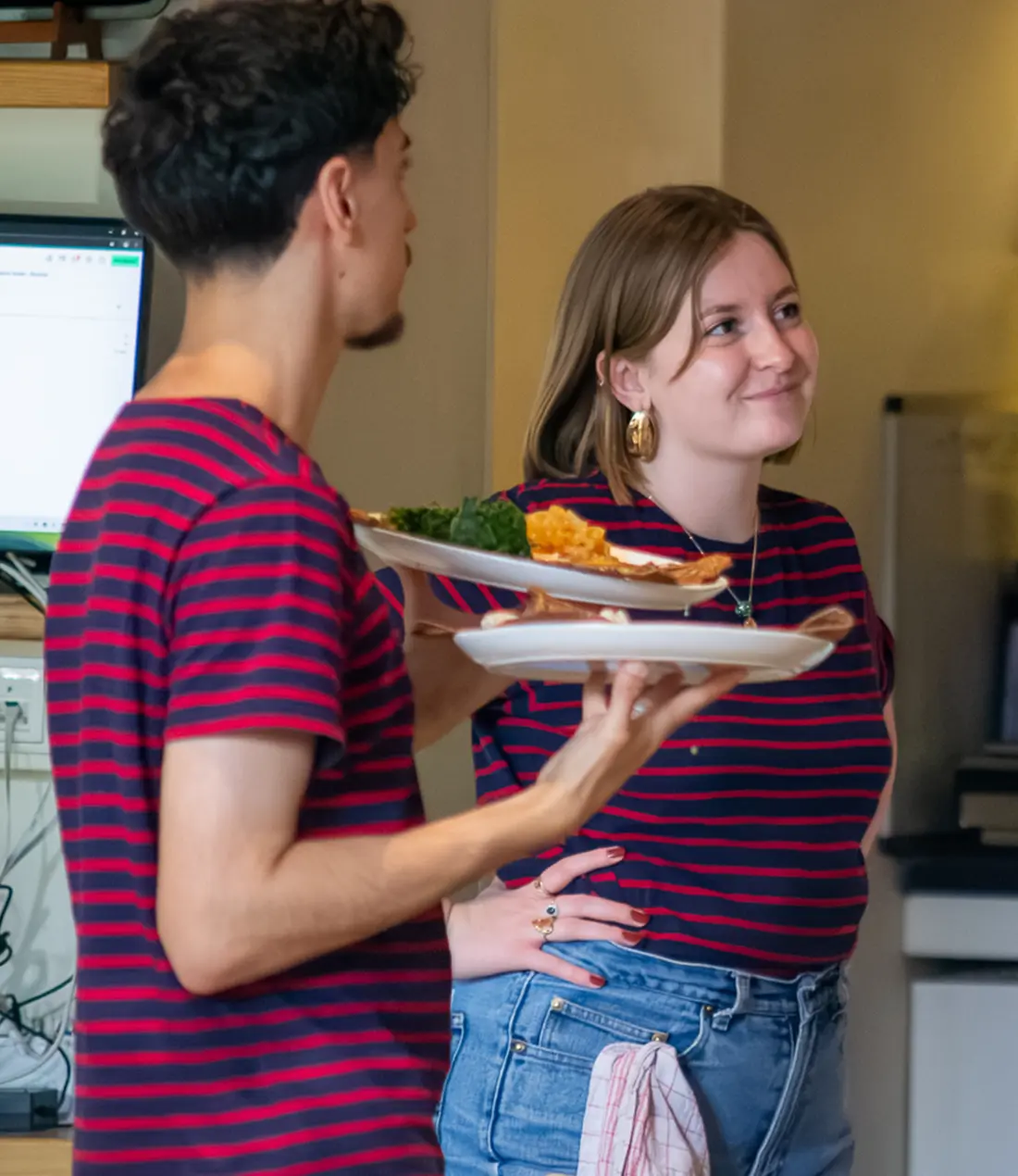 Zwei Mitarbeiter, einer hält zwei Speisen auf der Hand